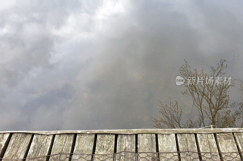 特写木码头与云彩和树梢倒映在湖中