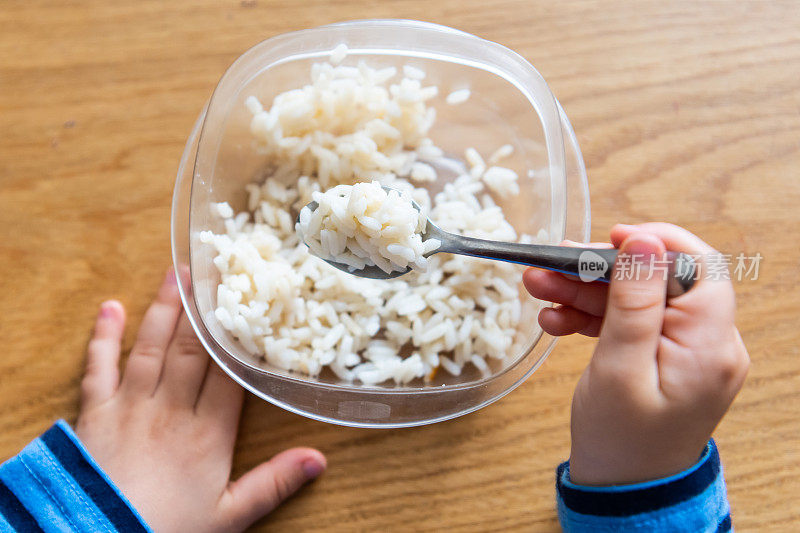 孩子手里拿着叉子，他正在吃米饭