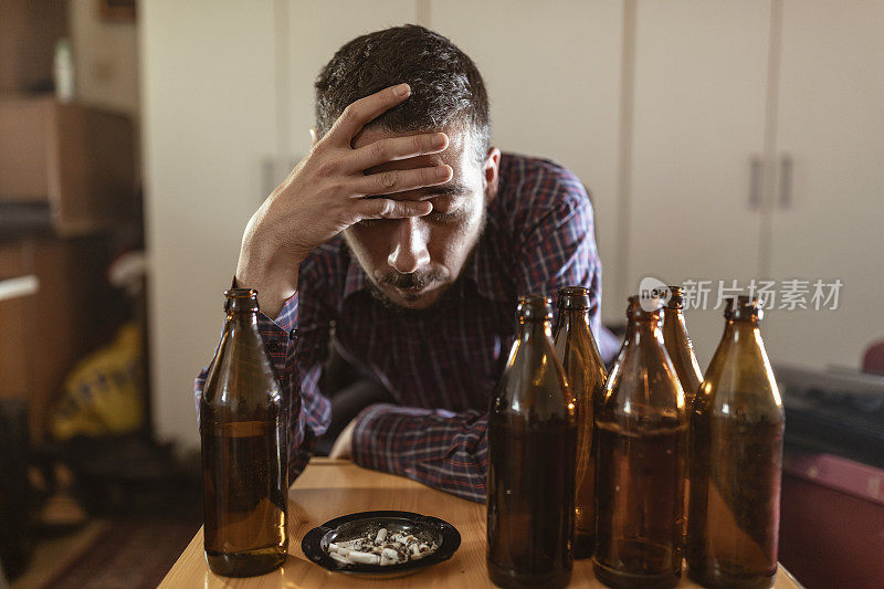 年轻悲伤的醉酒男子喝啤酒和酒精感到浪费，孤独和绝望的痛苦和情绪压力。人与酗酒、上瘾和男人抑郁的概念。