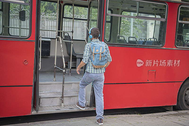 戴着耳机的年轻人正在上公交车