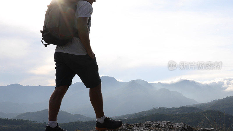 日出时分，男性徒步旅行者在山坡上休息