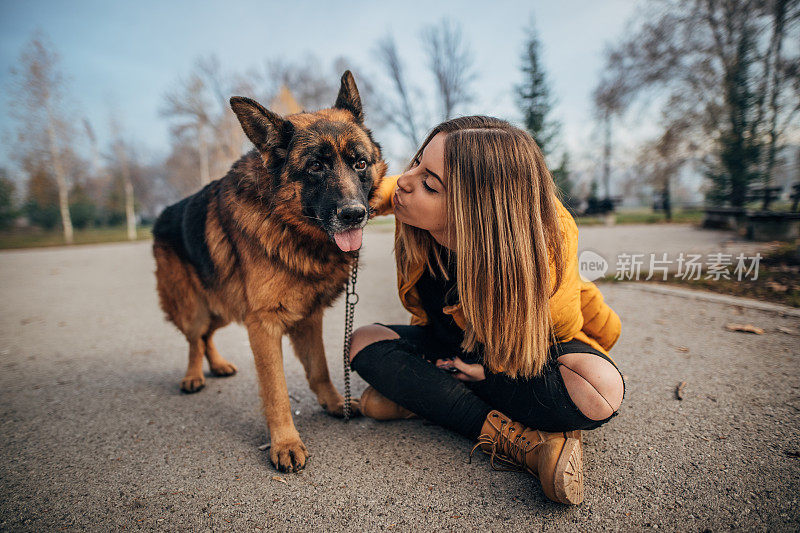 公园里有个年轻女人和一只德国牧羊犬