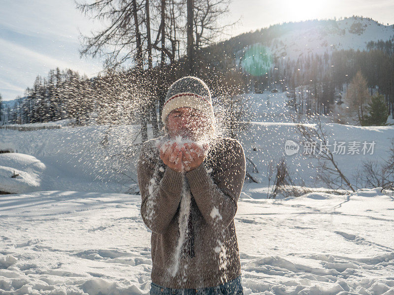 年轻人在冬日仙境里吹着粉雪
