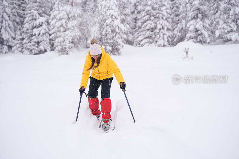 冬天的旅行者。年轻的女游客走在深深的雪中，享受冬天的山。肖像。