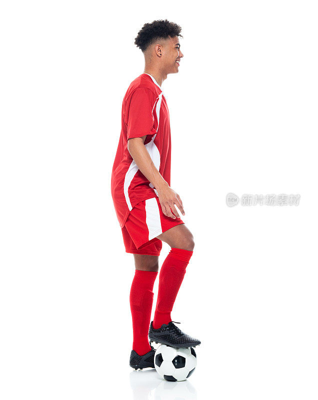 非裔美籍年轻男性运动员身穿足球制服站在白人背景前，手持足球进行足球运动和使用运动球