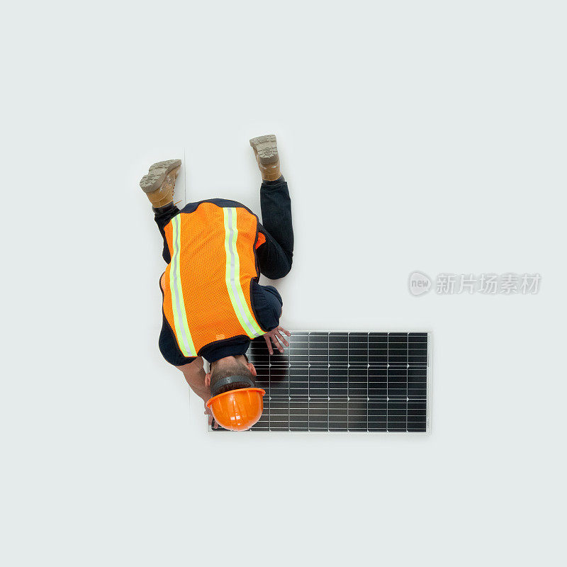 白种年轻男性体力劳动者穿着靴子和太阳能板跪在太阳能发电站的白色背景前