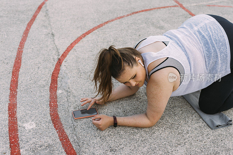 有曲线的女人用手机在户外锻炼，减肥的概念