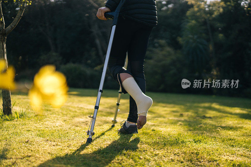 拄着拐杖的年轻女子在花园里休息