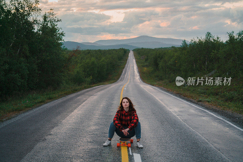 一名女子坐在芬兰公路上的长板上