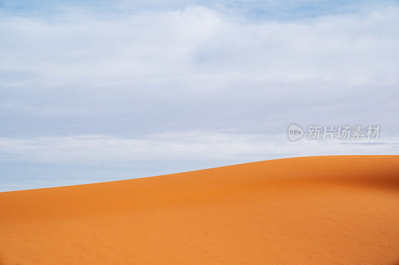 摩洛哥Merzouga沙漠的橙色沙丘和多云的天空。