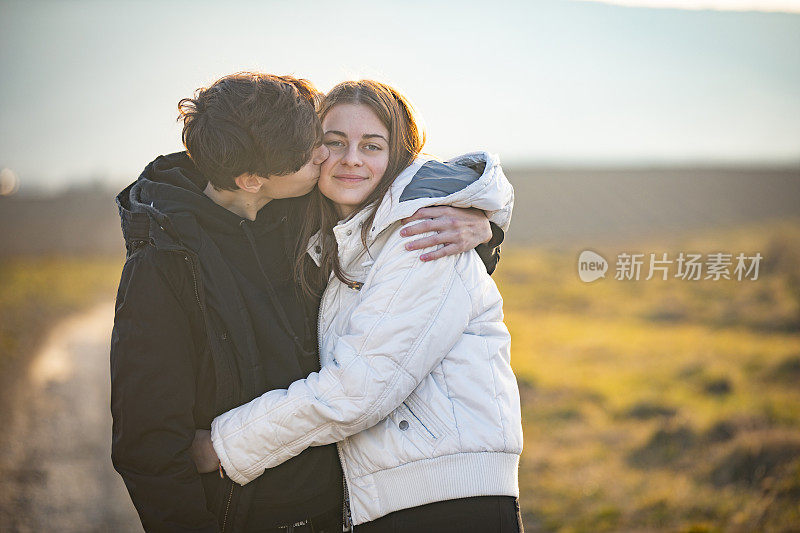 十几岁的男友亲吻女友的脸颊在户外的农村场景