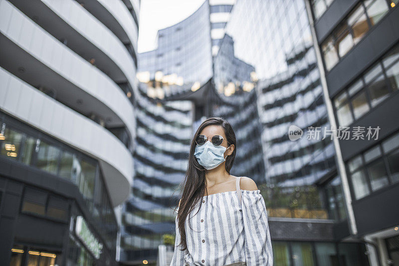 在新冠肺炎大流行期间，美丽的年轻女子戴着医疗脸在城市的肖像