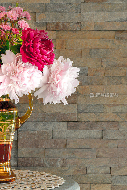 石墙背景上的花瓶里的花束