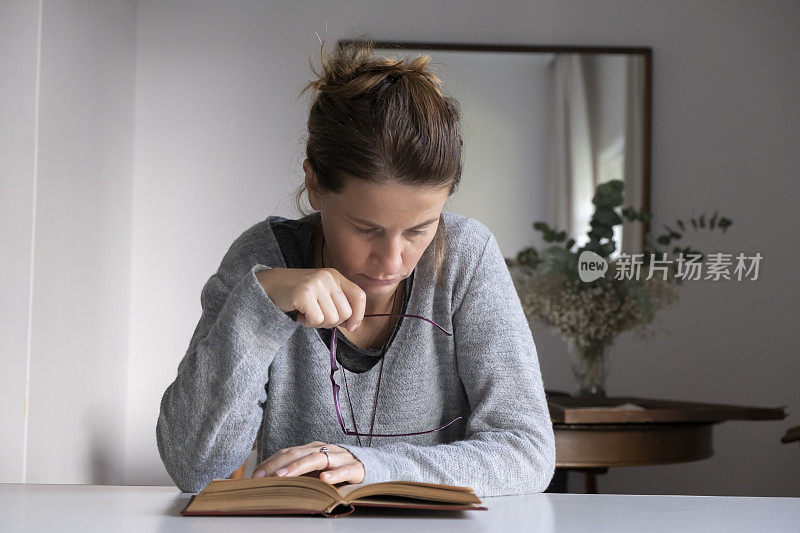 戴眼镜的女人在窗前看书