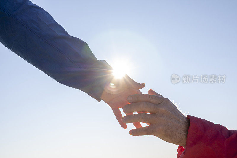 阳光下，女性徒步旅行者的手伸向男性的手