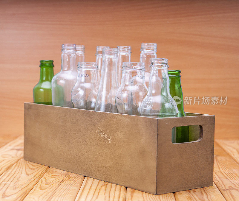 空玻璃瓶装在一个木箱里，放在木板上供回收利用