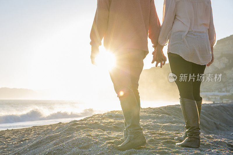 日出时分，一对情侣沿着海滩散步