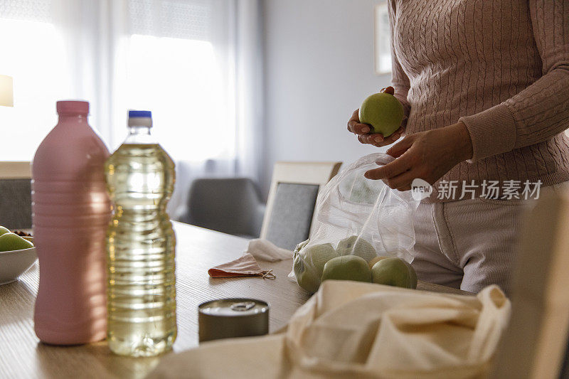 腹部的女人正在打开她从市场买的杂货