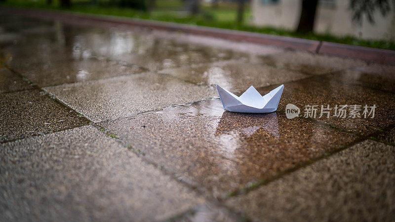 纸手工船玩具在一个水坑在一场雨