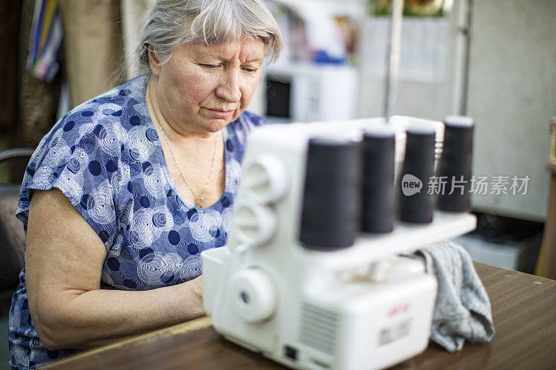 高级时装设计师在她的车间里使用缝纫机