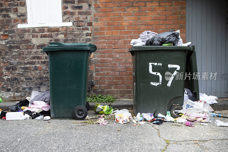 在英格兰北部城市的后街，两个有轮子的垃圾桶装满了垃圾