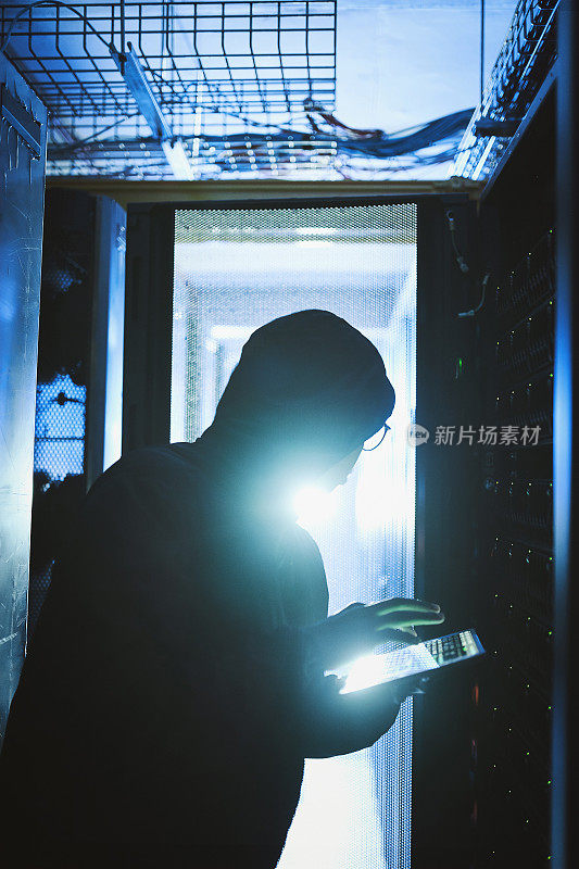 一名黑客在服务器室使用电子平板电脑