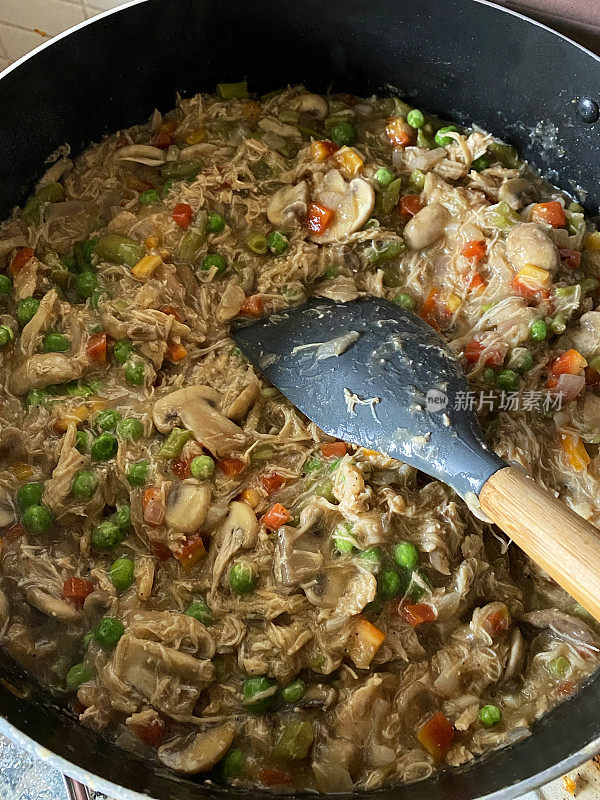 特写图像煮熟，鸡肉锅派食谱配料鸡肉丝，混合蔬菜，切片蘑菇，青豆，豌豆，洋葱丁不粘锅，炒锅，锅铲，高架视图