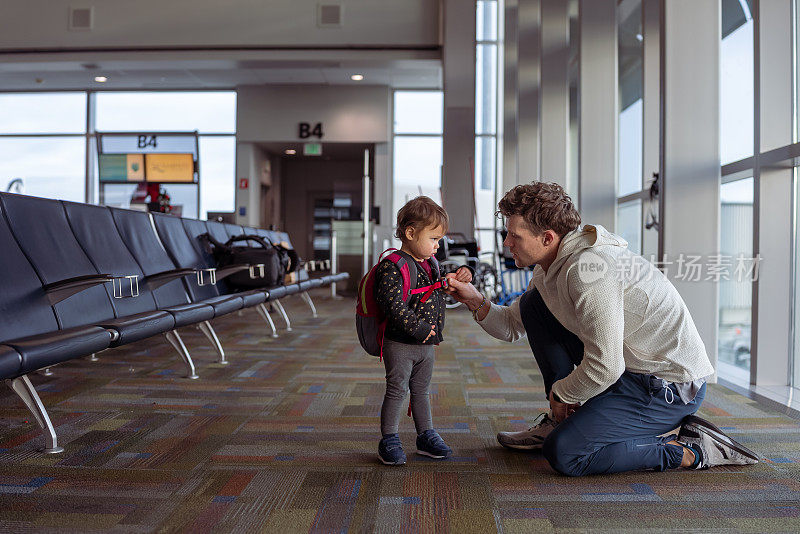 富有同情心的父亲在机场与蹒跚学步的女儿交谈