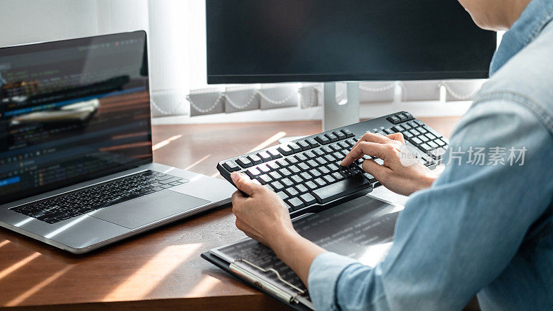 亚洲女性程序员看着键盘打字代码数据在笔记本电脑上的新项目，同时工作