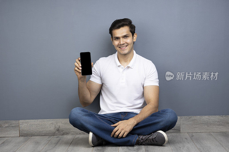 坐在地板上用手机的男人跷着腿，库存照片