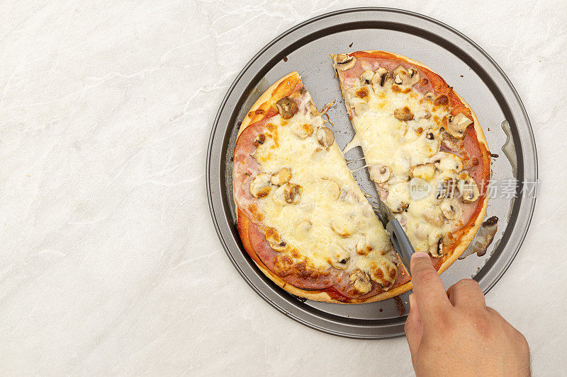 番茄酱、火腿、芝士和蘑菇的烤披萨俯视图。