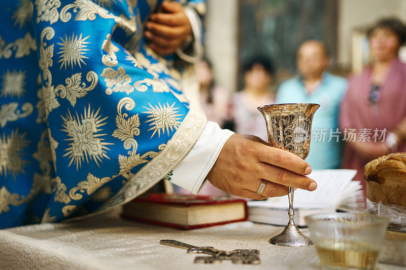在东正教教堂举行的婚礼仪式上，牧师的手和盛有酒的仪式婚礼杯