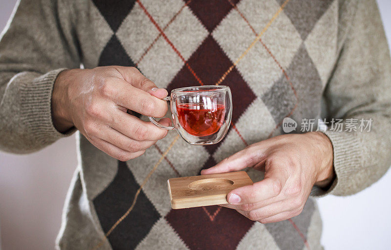 穿着冬衣的男人端着一杯茶