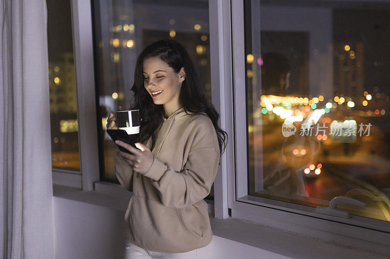 年轻女子在夜间使用智能手机的正面视图，背景是城市景观