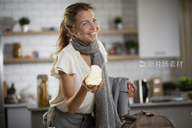 快乐的年轻女人在家里吃三明治。