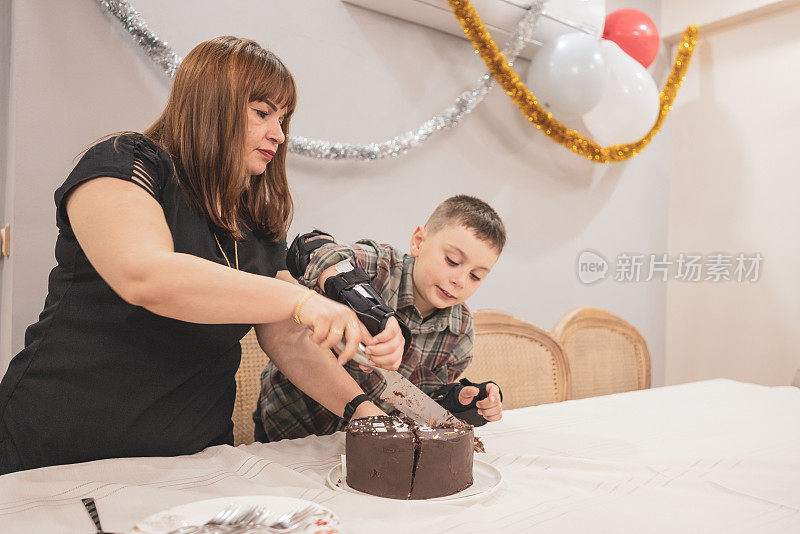 快乐的男孩在家里和妈妈一起切生日蛋糕