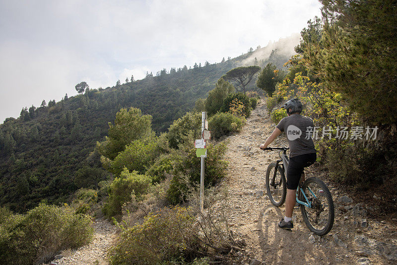 男性山地自行车手爬过山间的岩石小路