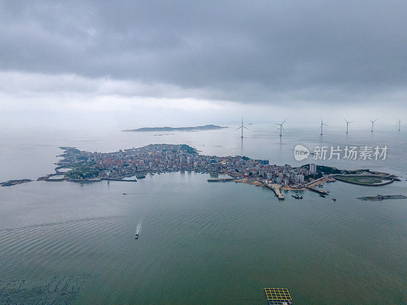 多云的天气，小岛的全景在海的中心和周围的风力发电