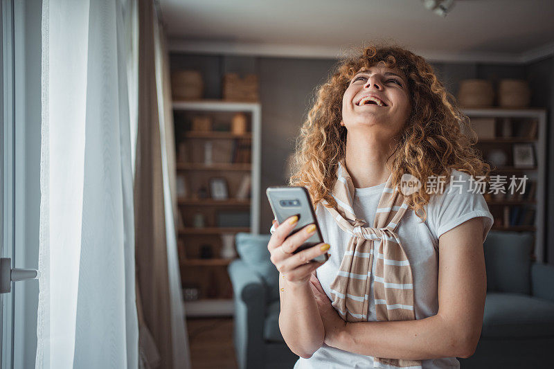 一个美丽的年轻女子正在她的公寓里用手机享受早晨