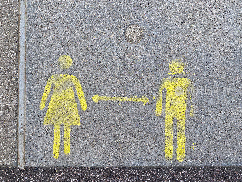 人行道上的男人和女人的彩绘标志，指示保持安全距离