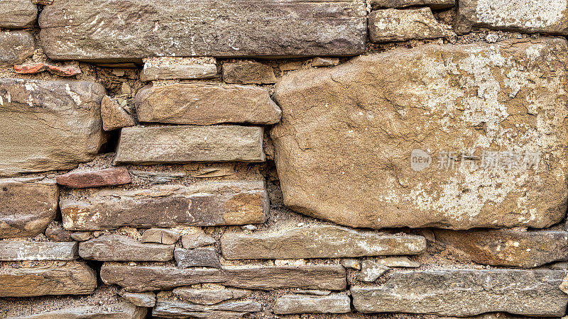 古老的石墙背景颜色各异。用一块块石头砌成的古老石屋的墙壁