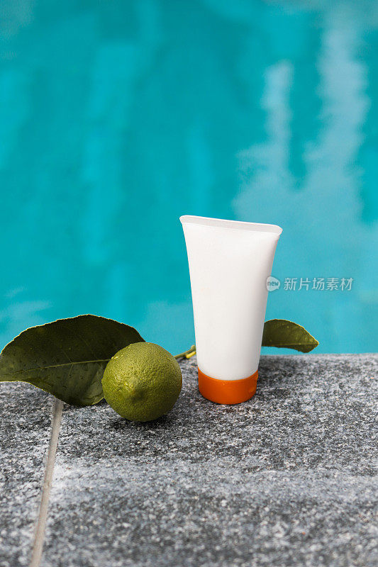 美容产品管包装在游泳池水面边缘与酸橙水果