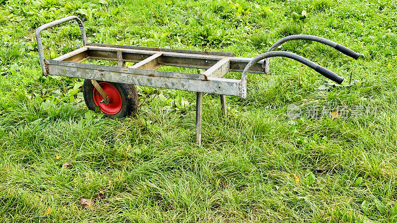 用来装植物的独轮车，空无一人地停在草地上