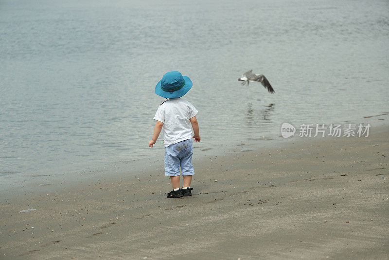 年轻的母亲带着她的小儿子在海滩上散步