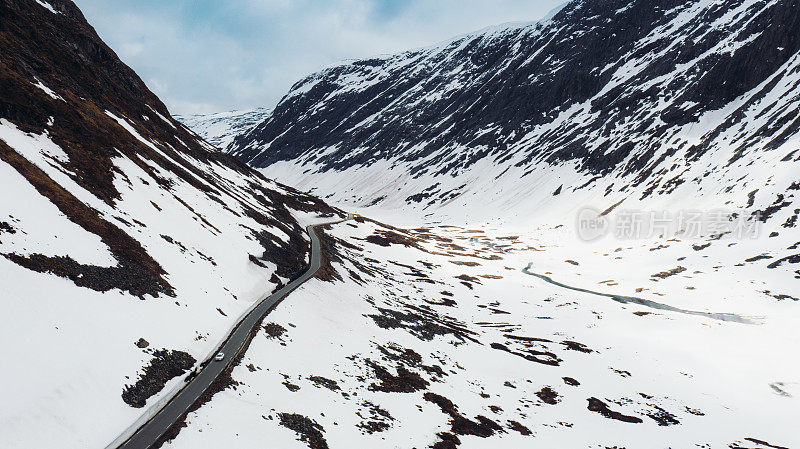 鸟瞰汽车在风景秀丽的道路上通过风景如画的雪山在挪威