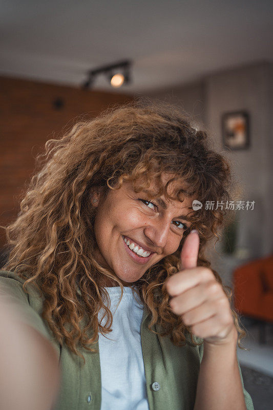 一名年轻卷发女子自拍或与朋友视频通话的照片