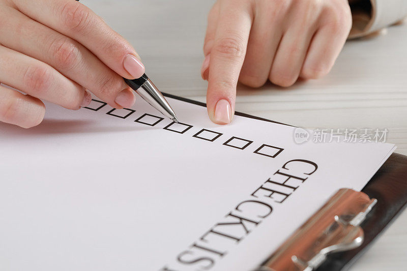 女人在白色木桌前填写检查清单，特写