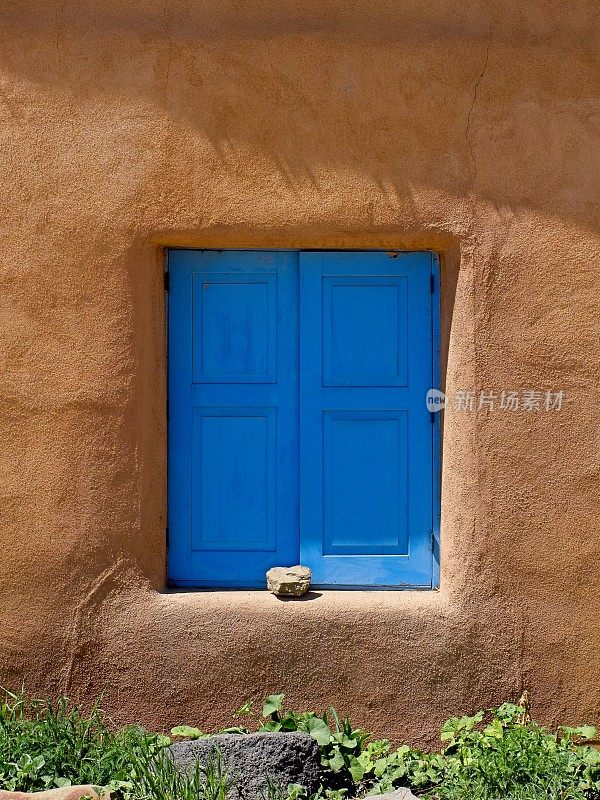 明亮的蓝色百叶窗与新墨西哥州阿尔伯克基老城的土坯墙形成鲜明对比