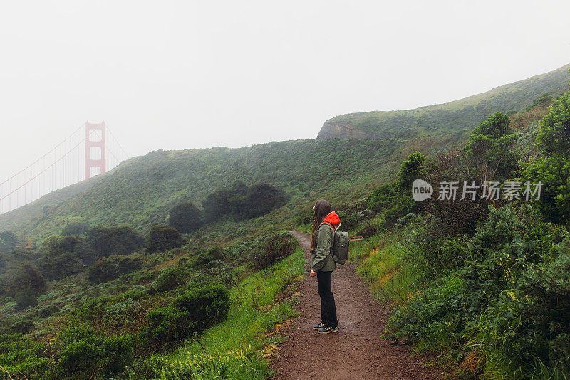 一名女子走在旧金山金门大桥的小山上