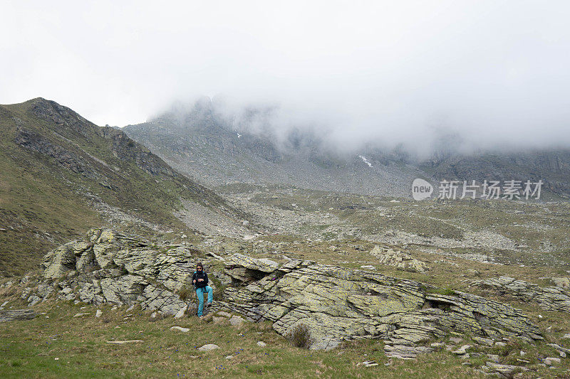 开创性的宁静:女徒步旅行者漫步在岩石草地上